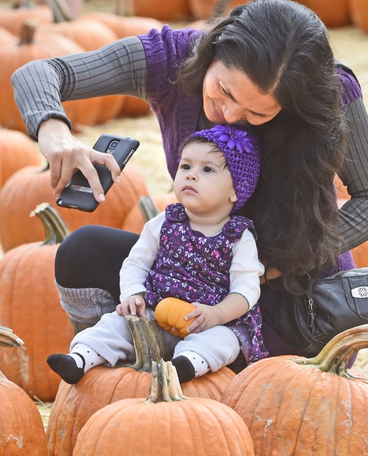 Wendy Jacobo and eight-month-old daughter Vanessa take a photo in the pumpkin patch at the inaugural Harvest Festival held at Gilchrist Farm in Saugus on Saturday. Dan Watson/The Signal