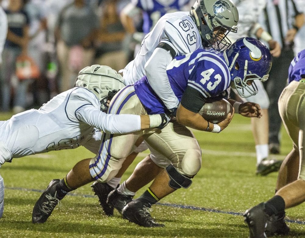 Valencia running back Moises Haynes (43) powers for first half yardage as Saugus defenders Blake Walkowiak (L) and Juan Esquivel (53) attempt to bring him down. Photo by Tom Cruze for The Signal.