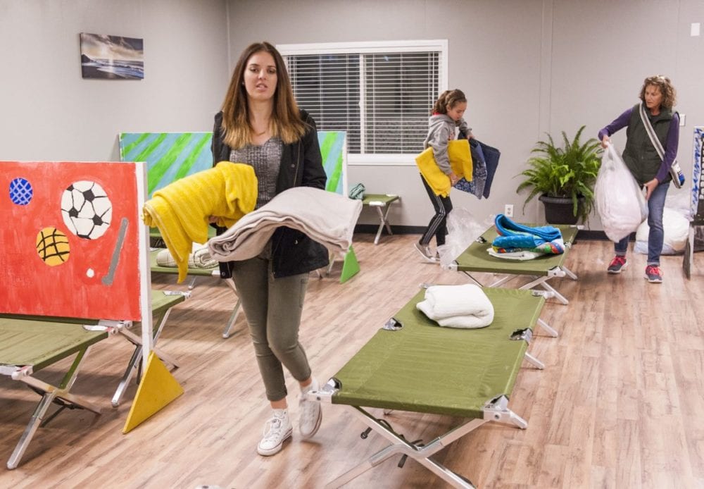 The Bridge to Home Shelter donations come from families, churches, scouts and businesses. Helping set up the sleeping quarters with blankets and towels are volunteers Haley (L) and Riley (C) Cabot and Resident Attendant Jayne Patafio (R). Photo Tom Cruze/For the Signal