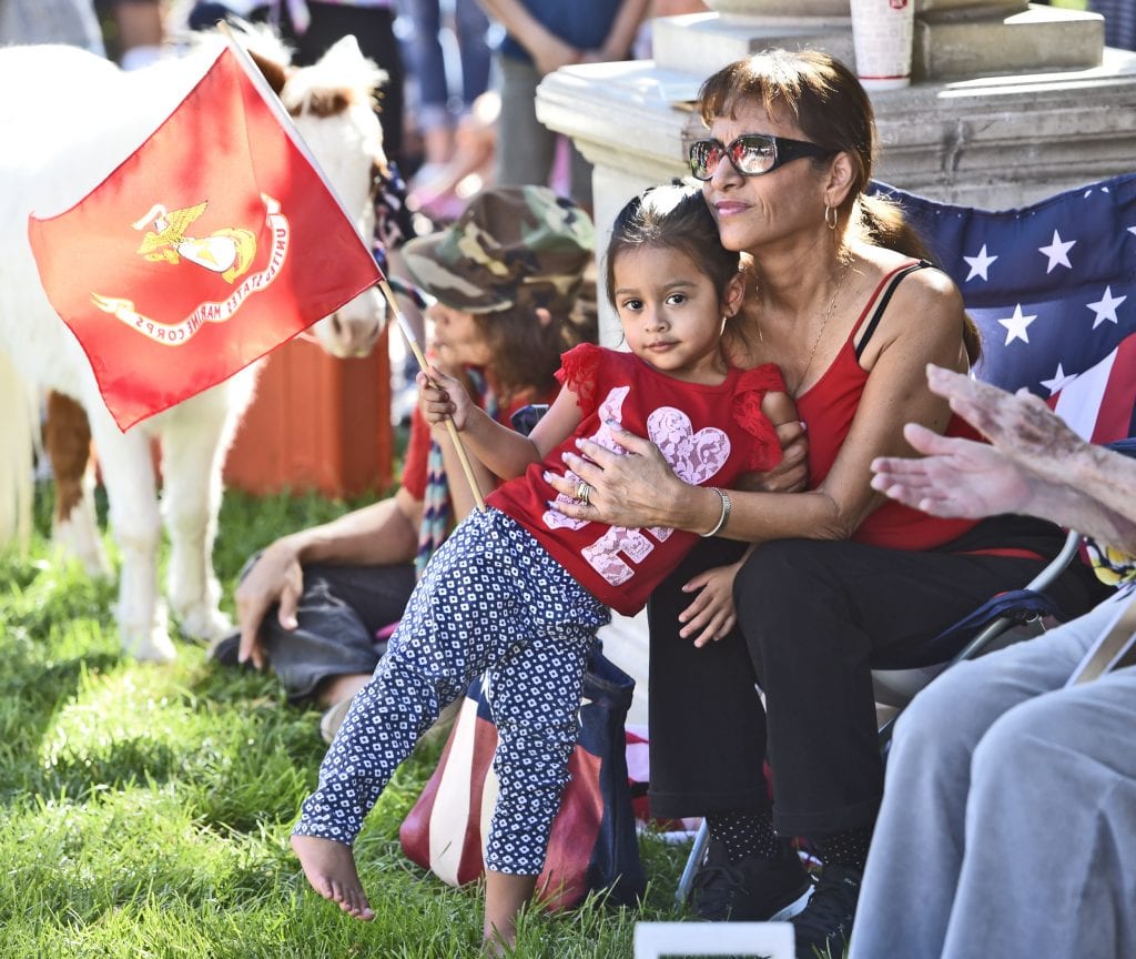 Irene Chavez, right, hugs Gigi Nava, 2, as she waves the flag of the U.S. Marine Corps as they join hundreds who attended the annual Veterans Day Ceremony held at Veteran's Historical park in Newhall on Friday. Dan Watson/The Signal