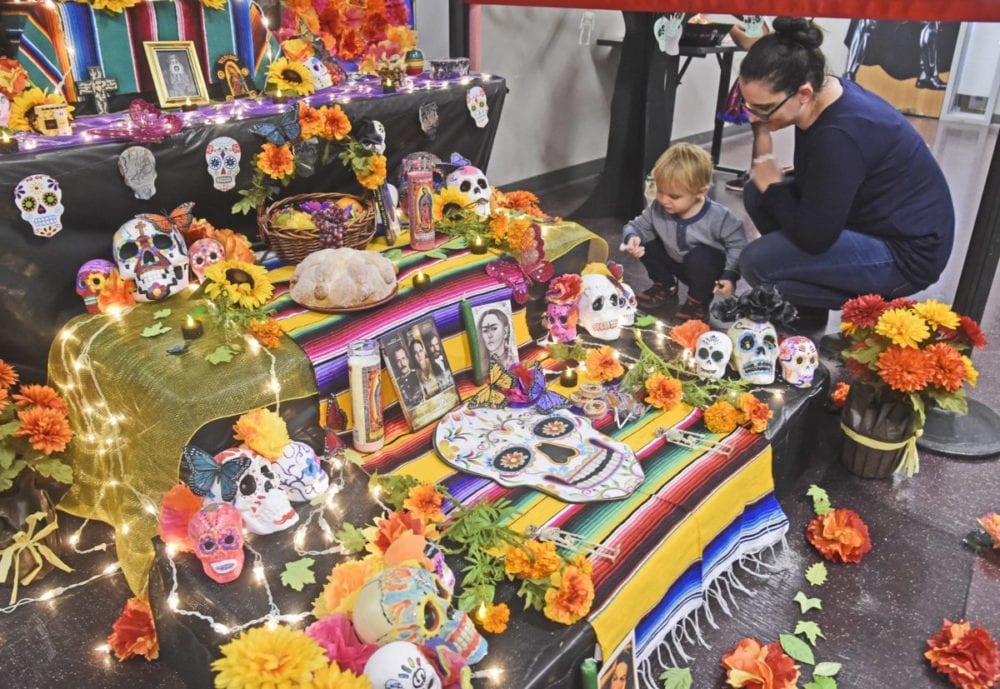 Michael Capella, 2,  left, and his mother, College of the Canyons student, Diana Capella take a close-up lokk at the Day of The Dead alter on display at the inaugural  Day of the Dead event  held at Mentry Hall at College of the Canyons in Valencia  on Tuesday. Dan Watson/The Signal