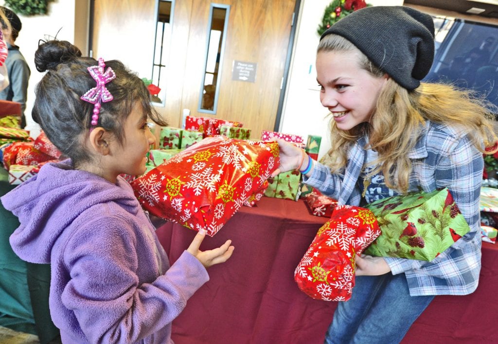 Yareni Galicia, 7, left, gets a gift from Sydney Jackson at the Festividad for Christ community event held at Faith Community Church in Newhall on Saturday. Dan Watson/The Signal