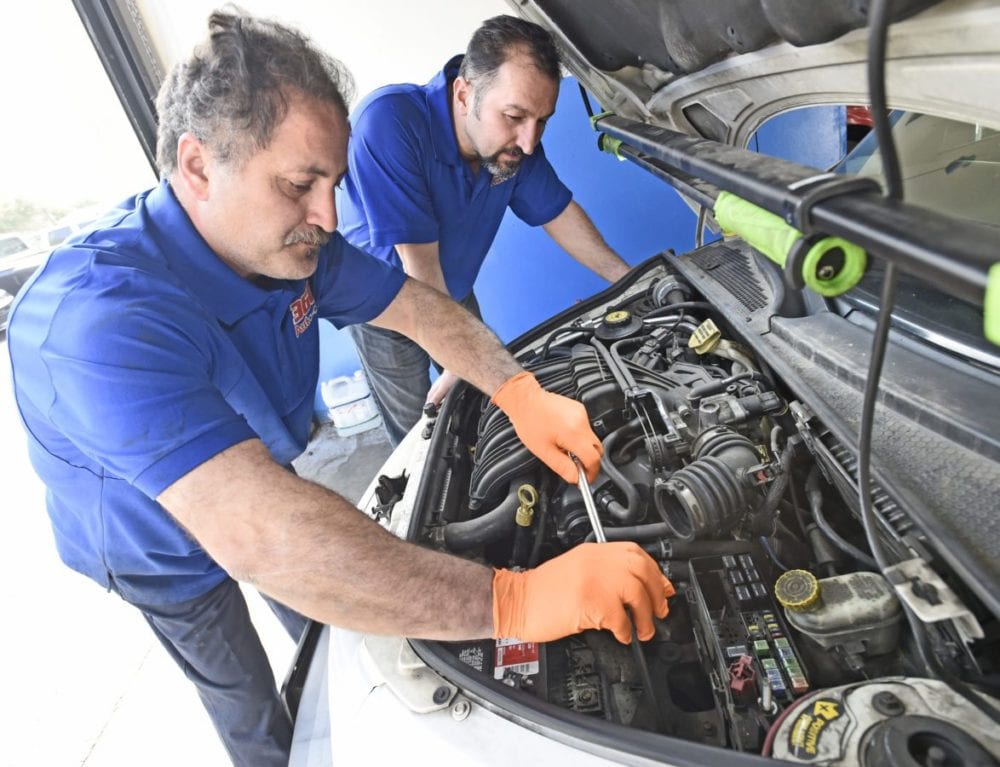 360 Auto Clinic Co-owners Armen Fanoosian, left, and Serjik Ghahramanians, install a new battery in the 2002 Chryser PT Cruiser they will be giving a way to a worthy person on December 22nd 2016 in Valencia.e car. Dan Watson/The Signal