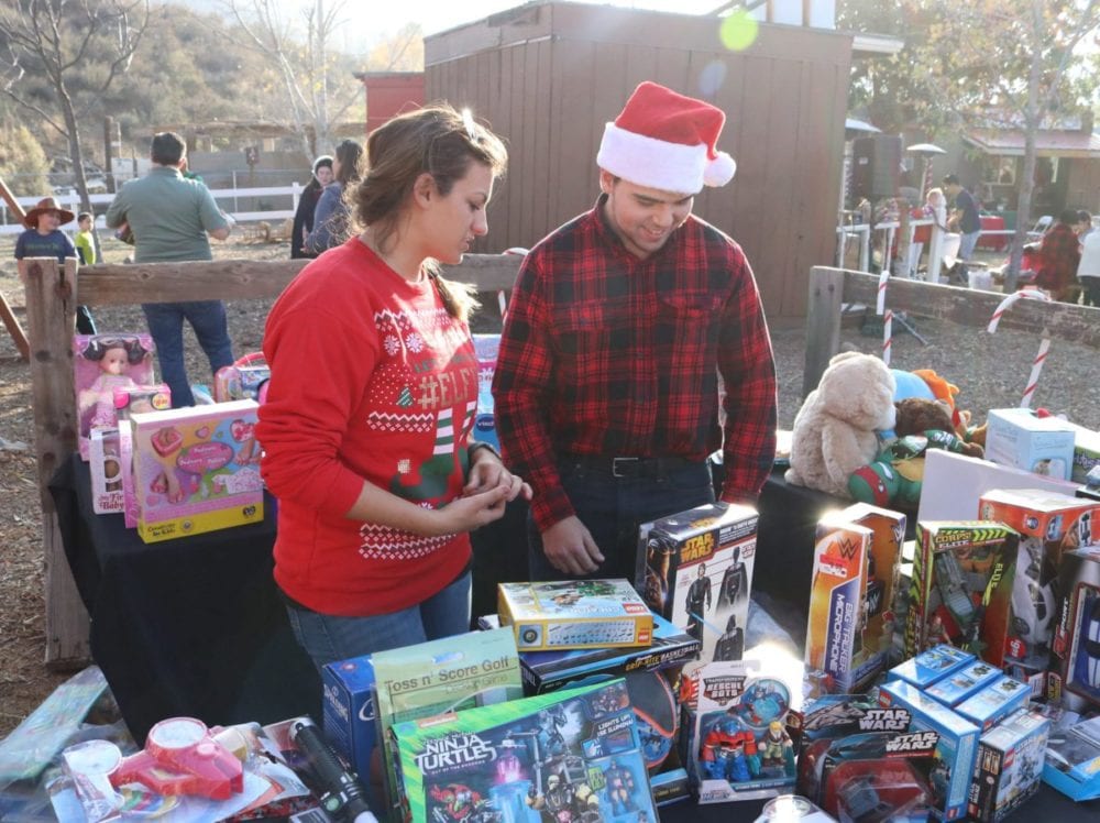 Janessa Yancy, left, and Brandon Ratner hand out presents to the children at Holiday Santa Day at Carousel Ranch in Santa Clarita on Saturday, Dec. 10, 2016. Nikolas Samuels/The Signal