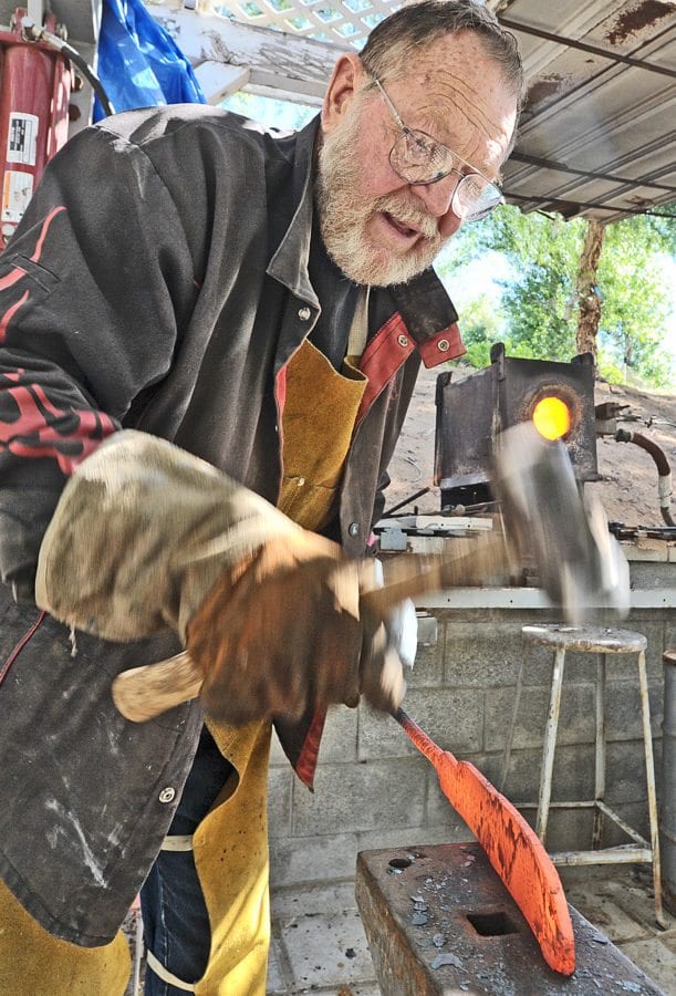 Bill Herndon uses a hammer on a hot steel blank to shape it into a blade. Dan Watson