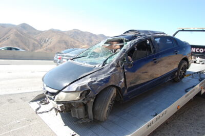 A vehicle involved in a collision with a dirt embankment that rolled over sits on a flatbed for towaway Thursday morning on southbound Highway 14 just north of Soledad Canyon Road.