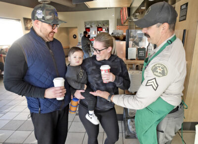 Santa Clarita Valley Sheriff's Station Deputy Evan Luster, right, chats with customers Cesar Cap, left, Sandra and Carson Cap, during the Coffee with a Cop event held at Starbucks in Canyon Country on Wednesday, 122822.