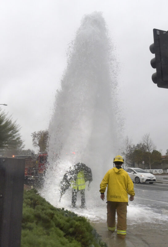 Los Angeles County Firefighters look for the shut off valve of a sheared fire hydrant at the corner of Magic Mountain Parkway and Valencia Boulevard in Valencia on Saturday, 123122.  