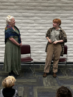 Ella Letton (Glynis Grafton, left) and Cora Walker (Rebecca Clark) participate in the storytime reading performance at the library. Courtesy photo.