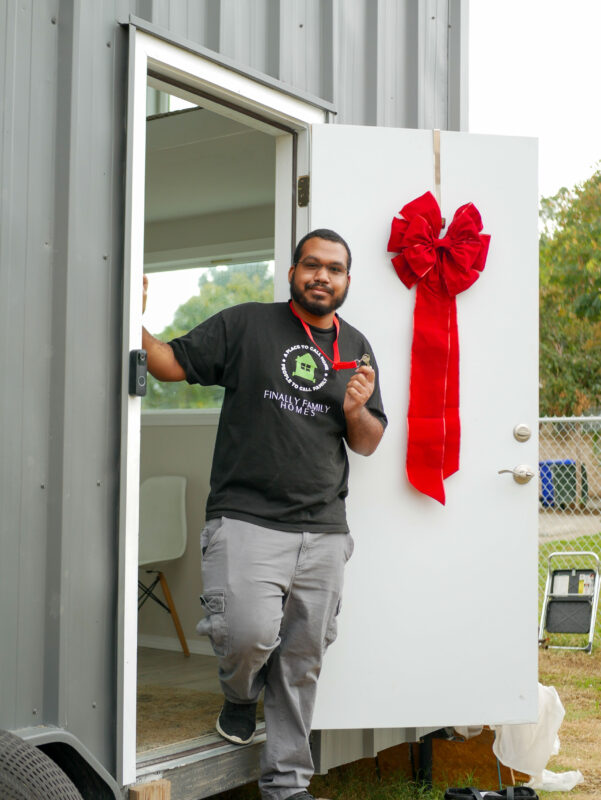 Zion Banks smiles proudly in front of the main entrance of his tiny home during the open house Saturday morning. Katherine Quezada/ The Signal