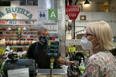 A fruit vendor at the Grand Central Market in Los Angeles, completes a transaction on Jan. 19, 2022. Photo by Pablo Unzueta for CalMatters