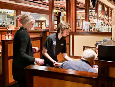 Charles Stockwell (right) delivers a plate of food to two restaurant guests while he job-shadowed a Salt Creek Grille employee on Thursday evening. Katherine Quezada/The Signal