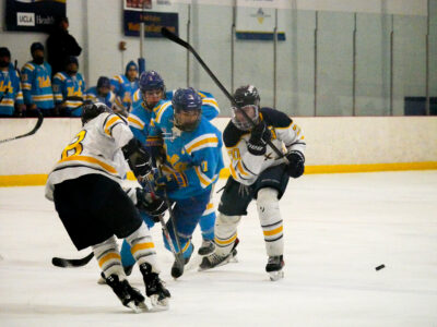John Ilvento (11) from UCLA passes the puck to another teammate while Jorden Werner (28) and Scott Bird (20) from NAU try to steal it during the West Coast Hockey Conference Championship at the Cube Ice and Entertainment Center on Sunday. Katherine Quezada/The Signal