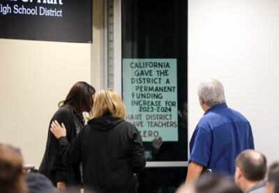 A member of the Hart District Teachers Association presses a protest sign against the window of the board meeting room during Wednesday's meeting. Habeba Mostafa/The Signal