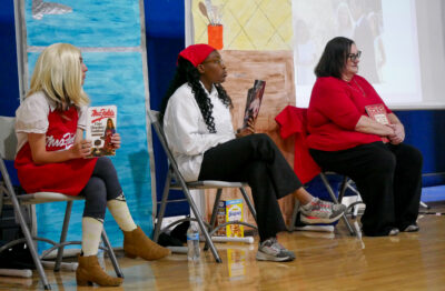 From left: Saugus High School freshman Lan Miranda, junior Aminat Arowolo, and English teacher Jodi Guerrero portray various successful female chefs and explain how they changed the world through their food and recipes during the 14th annual Women in History on Monday in the Saugus High School gym presented by the American Association of University Women. 040824 Katherine Quezada/The Signal