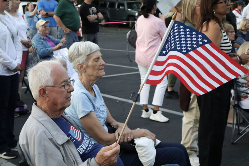 Brent Hoerner and Marja Hoerner sit with their flag and listen to the speaker at the Good Trouble Interfaith Vigil at Valencia United Methodist Church in Valencia, Thursday, July 17, 2025. Kamryn Martell/The Signal
