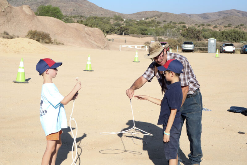 Vasquez Rocks volunteer Timothy Dodson (M, plaid shirt) teaches Connor Rismanchi (L, light blue shirt), 7, and Xander Young (R, dark blue shirt), 7, how to do lasso tricks at the Celebration of Western Songs at Vasquez Rocks in Agua Dulce, Sunday, July 13, 2025. Kamryn Martell/The Signal