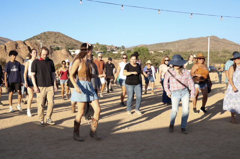 Anais Cordebard (L, brown shirt, denim skirt), line dance instructor, teaches attendees some moves at the Celebration of Western Songs at Vasquez Rocks in Agua Dulce, Sunday, July 13, 2025. Kamryn Martell/The Signal