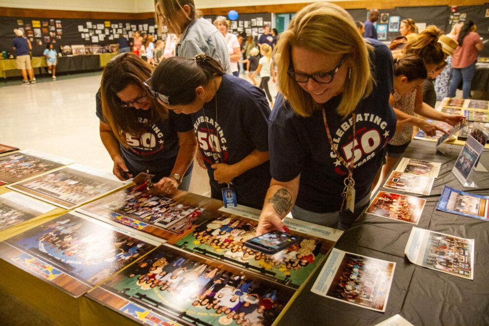 Meadows Elementary teachers and staff Melanie Musella (front), Sarah Yuhan (center) and Sheldy Levine look through past photos during the 50th birthday of Meadows on Sept. 5, 2025. Katherine Quezada/The Signal