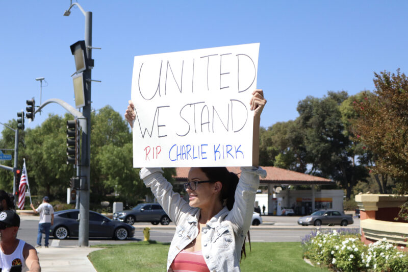 Kendra Tally holds up a sign at the memorial for Charlie Kirk at the intersection of McBean Parkway and Valencia Boulevard, Sunday, Sept. 14, 2025. Kamryn Martell/The Signal