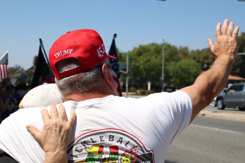 Jeanette Lutton (L) and Roger Fowble (R) hug each other and wave at the memorial for Charlie Kirk at the intersection of McBean Parkway and Valencia Boulevard, Sunday, Sept. 14, 2025. Kamryn Martell/The Signal