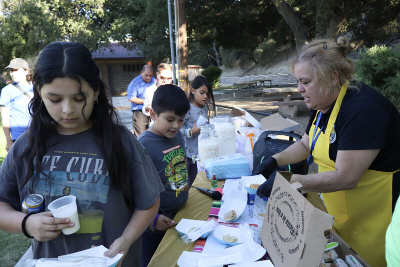 Micaela Gonzalez (R, yellow apron), recreational services leader for Val Verde Park, passes out tamales to attendees at the second installment of Los Angeles County's Hispanic Heritage Month celebration at Val Verde Park in Val Verde, Calif. on Thursday, Sept. 25, 2025. Kamryn Martell/The Signal