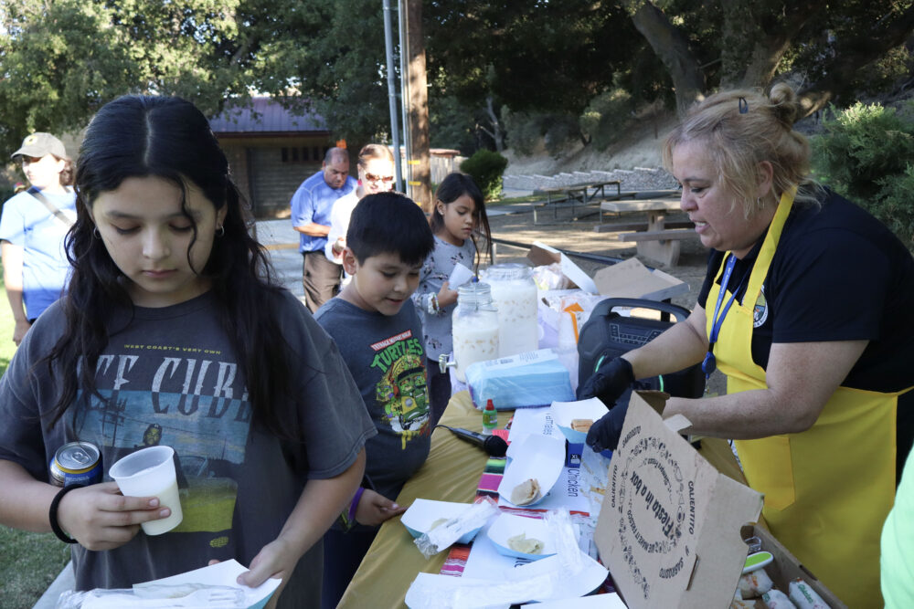 Micaela Gonzalez (R, yellow apron), recreational services leader for Val Verde Park, passes out tamales to attendees at the second installment of Los Angeles County's Hispanic Heritage Month celebration at Val Verde Park in Val Verde, Calif. on Thursday, Sept. 25, 2025. Kamryn Martell/The Signal