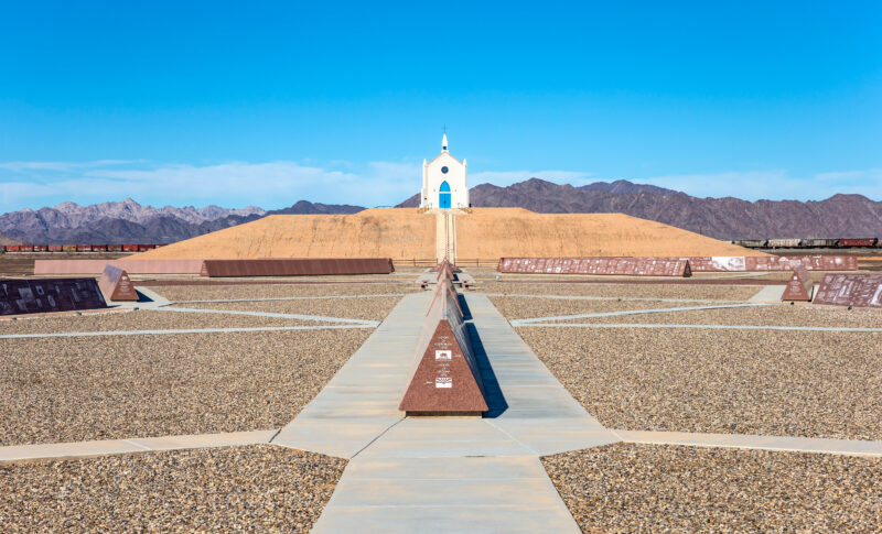 The Chapel of the Desert a small religious sanctuary situated atop a 35-foot man-made hill. The iconic cream-colored structure with its turquoise blue door stands out against the muted colors of the desert. ©SHUTTERSTOCK