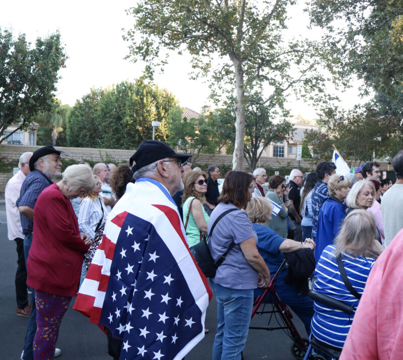 A man drapes an American flag over himself at the "October 7th" memorial at the City of Santa Clarita City Hall, Sunday, Oct. 5, 2025. Kamryn Martell/The Signal