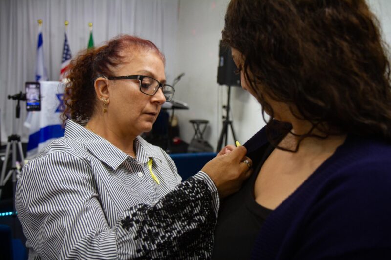 Lana Aiachi places a yellow ribbon on Nawal Helo before the start of the Flags and Fellowship of Jews and Christians prays before the “Remembering Oct. 7” ceremony on Oct. 7, 2025 in Canyon Country, Calif. Katherine Quezada