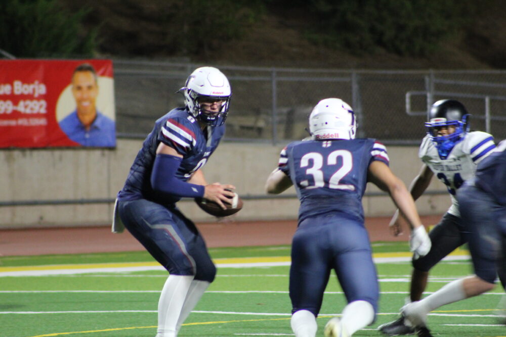 Trinity quarterback Andrew Carlson, left, hands the ball off to running back Hudson Sweitzer (32) during the game at Cougar Stadium on Oct. 11, 2025. Ryan Romero/The Signal