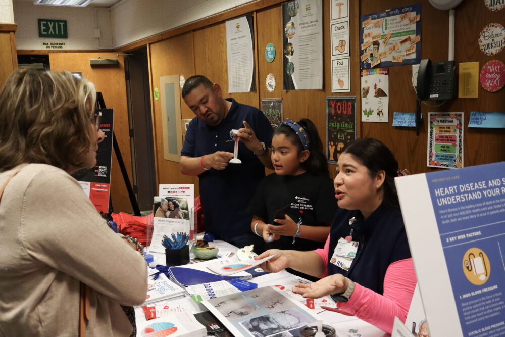 Donna Ganshirt (L, beige sweater) talks to Judy Bravo (R, pink long sleeve) about strokes at the Our Lady of Perpetual Help Health & Wellness Fair at OLPH in Newhall, Calif., Sunday, Oct. 19, 2025. Kamryn Martell/The Signal