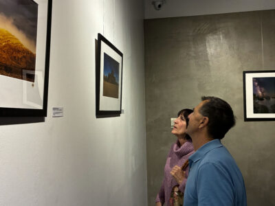 Ron Petersen (blue shirt) and Mary Petersen (purple sweater) look at "Devils Playa by Moonlight" at the photographer David Brix's "Far Out Places" reception at Teacision Tea House in Newhall, Calif., Sunday, Nov. 9, 2025. Kamryn Martell/The Signal
