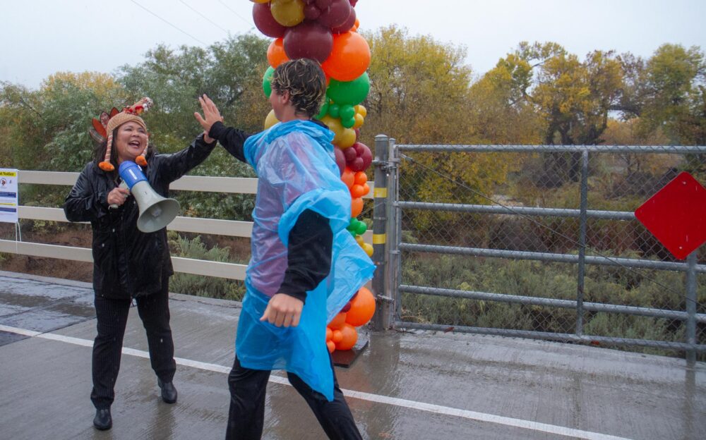Bridge to Home Interim Executive Director Courtney Kanagi high fives a Turkey Trot participant as he completes the run amid a heavy down pour in Valencia on Saturday, Nov. 15, 2025. Katherine Quezada/The Signal