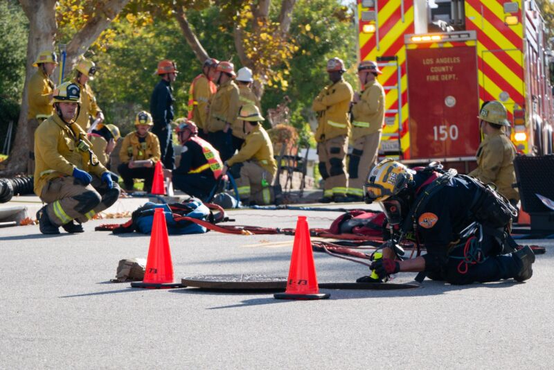 An official with the Los Angeles County Fire Department’s Urban Search & Rescue looks down through a sewer during a rescue operation to locate a dog on Monday, Nov. 24, 2025. Katherine Quezada/The Signal
