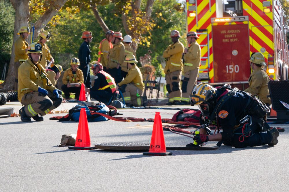 An official with the Los Angeles County Fire Department’s Urban Search & Rescue looks down through a sewer during a rescue operation to locate a dog on Monday, Nov. 24, 2025. Katherine Quezada/The Signal