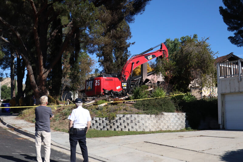 Onlookers watch the house get cleaned up at the 29100 block of Flowerpark Drive in Canyon Country, Calif., Sunday, Dec. 14, 2025. Kamryn Martell/The Signal