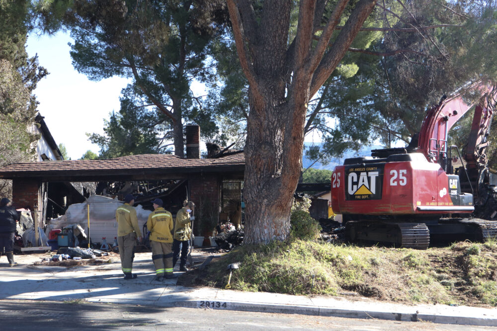 Los Angeles County Fire Department personnel observe the damage after the structure fire at the 29100 block of Flowerpark Drive in Canyon Country, Calif., Sunday, Dec. 14, 2025. Kamryn Martell/The Signal