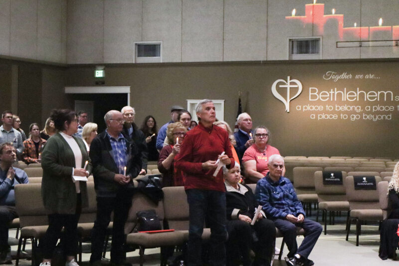 Attendees stand up to light their candles at the Santa Clarita Valley Chapter of Compassionate Friends 24th annual Candlelight Remembrance Program at BethlehemSCV in Canyon Country, Calif., Sunday, Dec. 14, 2025. Kamryn Martell/The Signal