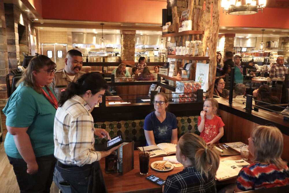 Justin Miyahira (facial hair, back), a Search and Rescue volunteer, Lindsay Kautiainen (blue shirt, center), a Special Olympian, and Taran Semerdijian (plaid shirt, front), a server at Lazy Dog Restaurant & Bar, at the Special Olympics Southern California's "Tip-a-Cop" at Lazy Dog in Valencia, Calif., Tuesday, March 3, 2026. Kamryn Martell/The Signal