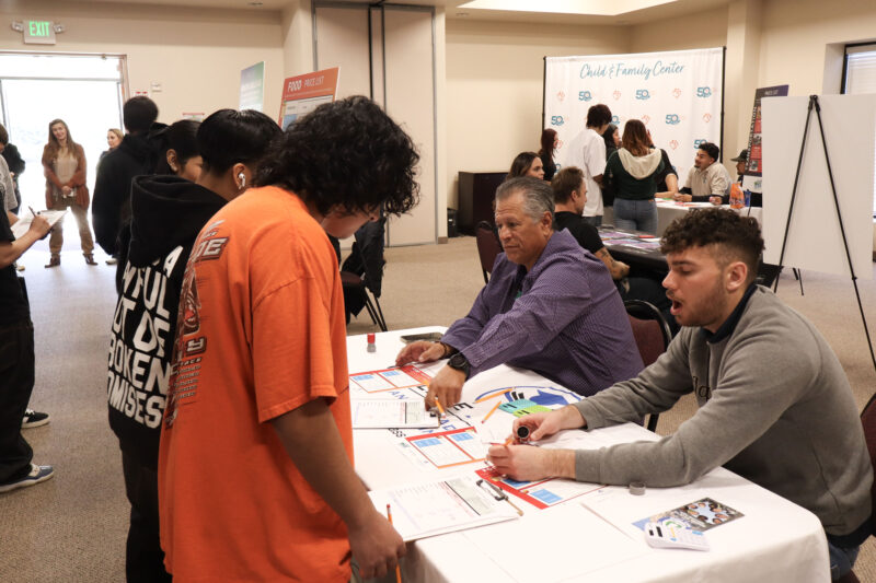 Rudy Herrera (left, purple shirt) and Ben Minkin (right, gray shirt) help Bowman High School students at the College Assurity booth at the JCI Santa Clarita's "Get Real: Adulting 101" financial literacy event at Child & Family Center in Canyon Country, Calif., Wednesday, March 4, 2026. Kamryn Martell/The Signal