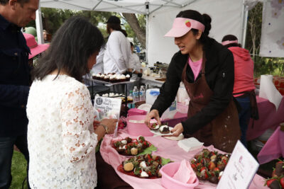 Paulina Cisneros (R) hands out chocolate-covered strawberries at Clarice's booth at the Child & Family Center's 37th annual "Taste of the Town" at the SoCal Innovation Park in Valencia, Calif., Sunday, May 3, 2026. Kamryn Martell/The Signal