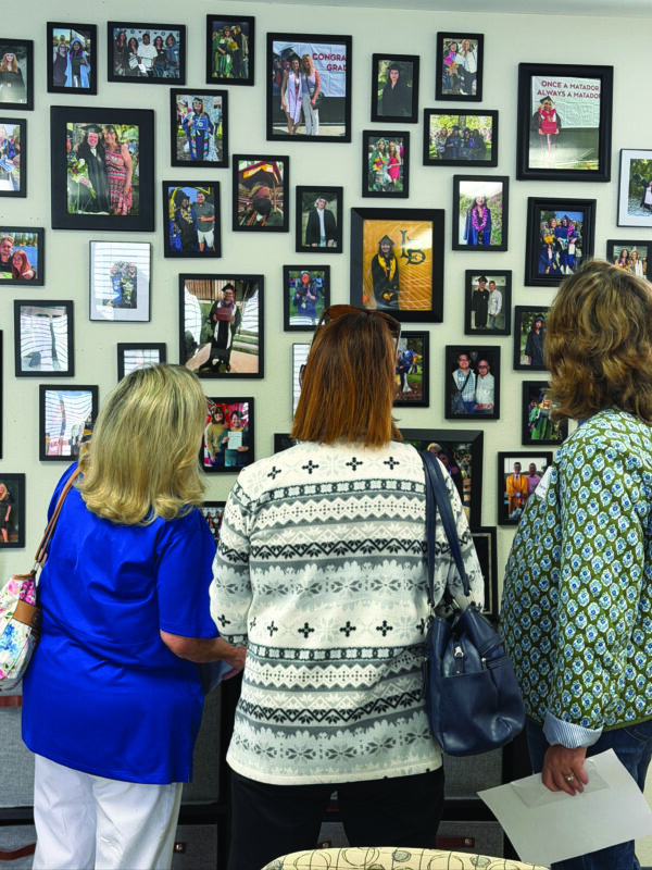 Visitors to the Fostering Youth Independence open house on April 25 view photos of the program’s graduates. Courtesy photo.