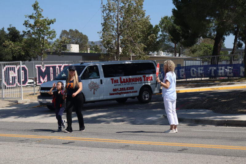 A woman holding a stop sign signals traffic during school pickup at Sulphur Springs Community School in Canyon Country, Calif., Thursday, May 21, 2026. Kamryn Martell/The Signal
