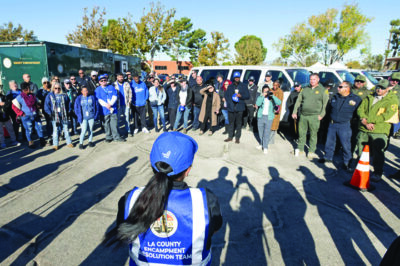Los Angeles County Sheriff's Department Homeless Outreach Services Team (HOST) deputies, pictured at right, participate in a multidisciplinary team briefing before a homeless encampment operation in the Antelope Valley in November 2024. (Photo credit: Diandra Jay/Los Angeles County)
